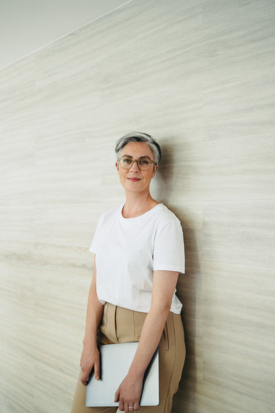 Grey-haired businesswoman standing against a wall in an office