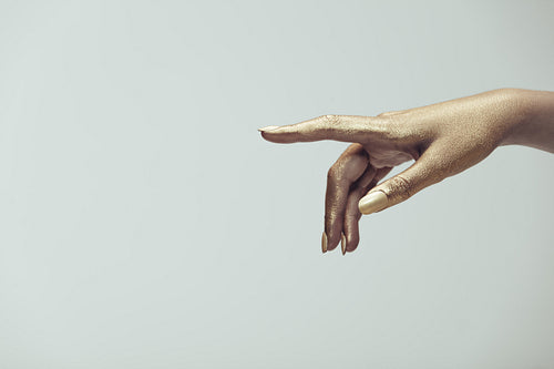 Golden painted hand pointing at copy space