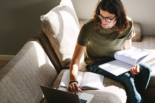 Student sitting at home and studying using laptop