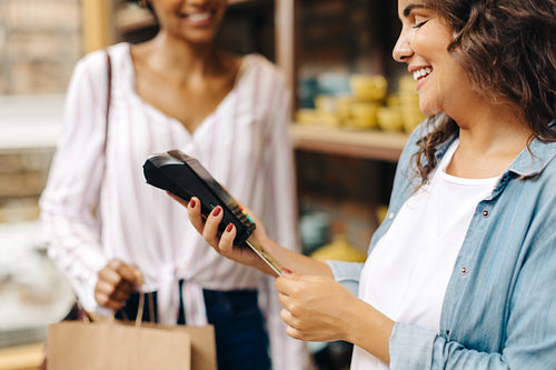 Happy ceramic store owner doing a cashless transaction in her shop
