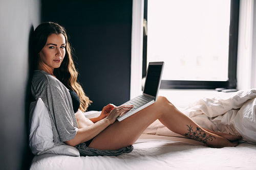 Female in lingerie on bed with a laptop