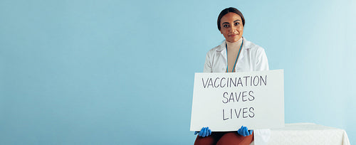 Healthcare worker with "Vaccination saves lives" banner