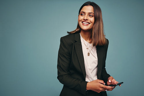 Cheerful young woman holding a mobile phone in a studio