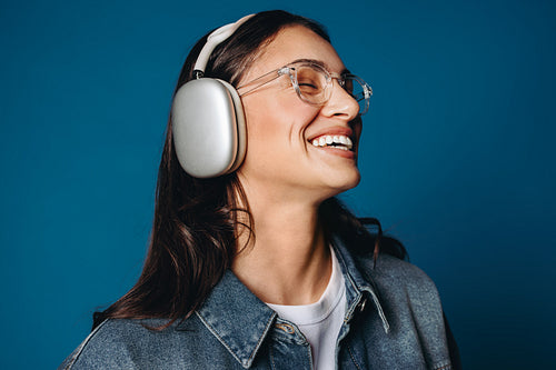 Close up of a woman wearing headphones and smiling wearing glasses