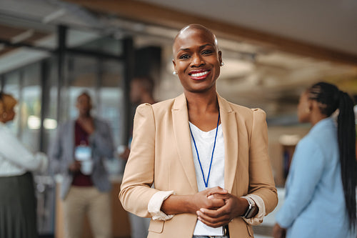 Confident professional woman smiling in office environment with colleagues in background