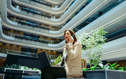 Professional businesswoman on phone in modern office courtyard