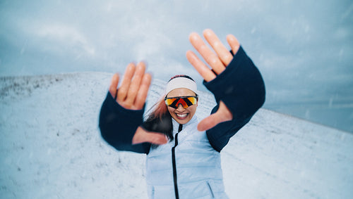 Woman training in winter snow with playful smile during outdoor fitness workout