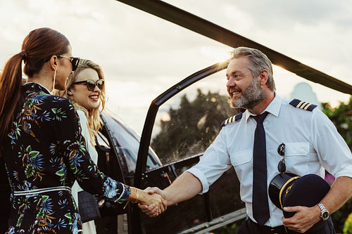 Helicopter pilot shaking hands with two women