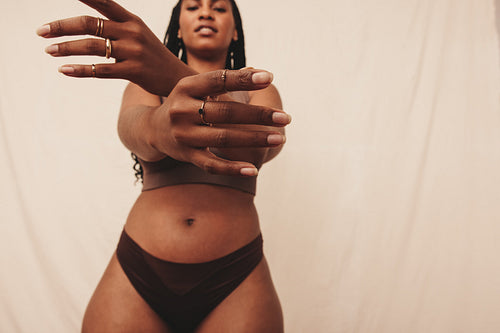 Young woman extending her hands towards the camera in a studio