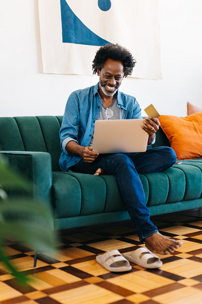Happy man enjoying online shopping at home with a laptop and a credit card