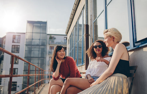 Three young female friends sitting in balcony
