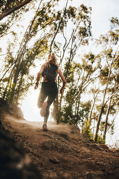 Woman running up hill on mountain trail