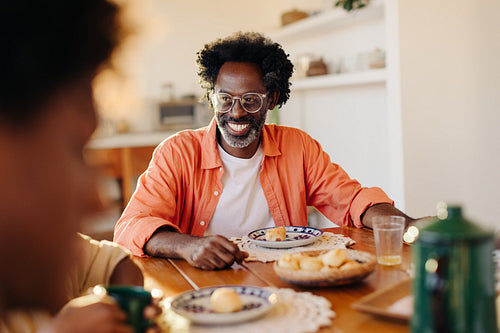 Happy family enjoying a delicious Brazilian breakfast with cheese bread rolls and coffee
