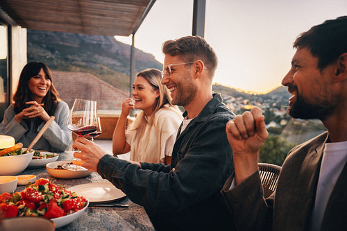 Group of young friends enjoying dinner and wine on a cozy patio