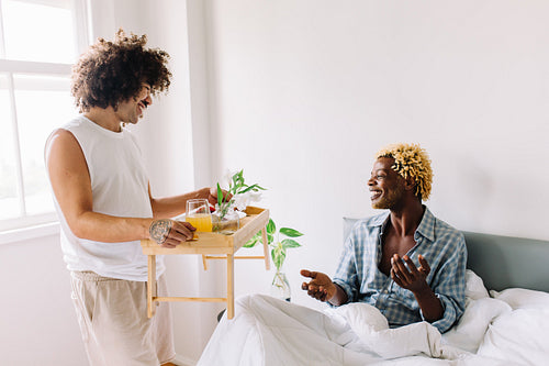 Affectionate young gay man spoiling his lover with breakfast in