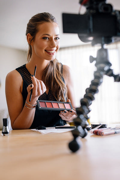 Young female vlogger recording a make-up video for her vlog.