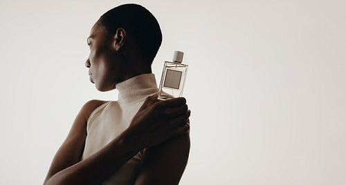 Elegant woman holding perfume bottle for luxury branding mockups