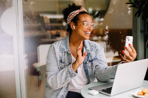 Business woman working remotely in coffee shop using a smartphone for video chatting