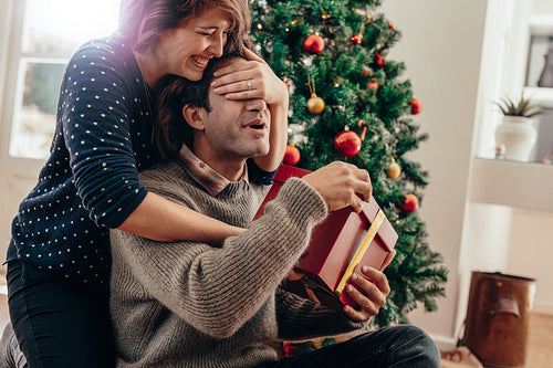 Young couple having fun celebrating Christmas with gifts.