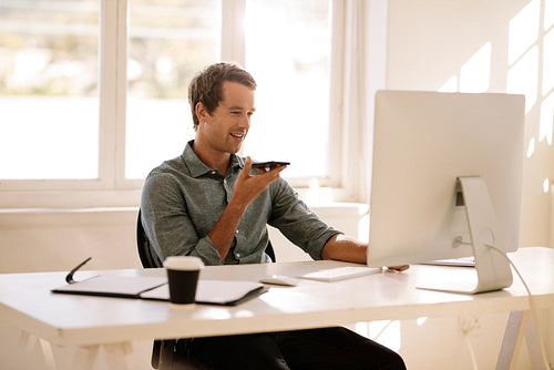 Entrepreneur talking on mobile phone while working on computer at home