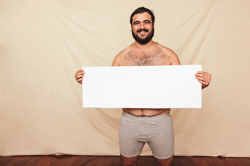Body positivity activist holding a placard in a studio