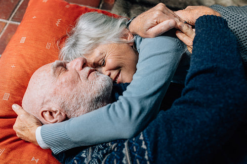 Senior couple expressing love embracing each other lying on floor