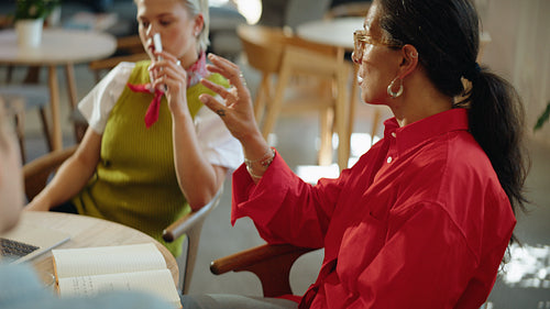 Woman and coworkers review notes during a team meeting at a cafe table