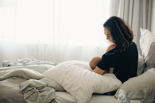 Mother breastfeeding baby at home