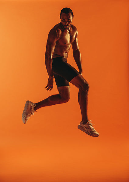 Muscular man jumping in air during workout