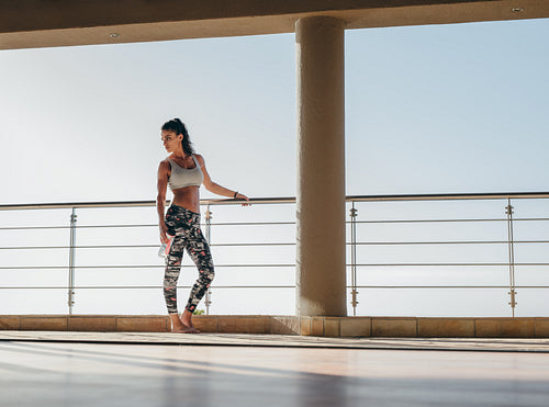 Fit woman standing in the balcony with water bottle