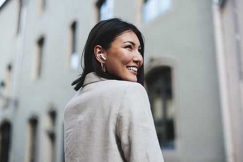 Happy woman listening to an audiobook in the city
