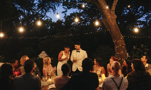 Intimate garden wedding celebration under string lights with friends and family