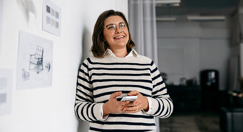 The woman handles communication on her smartphone in a creative design office