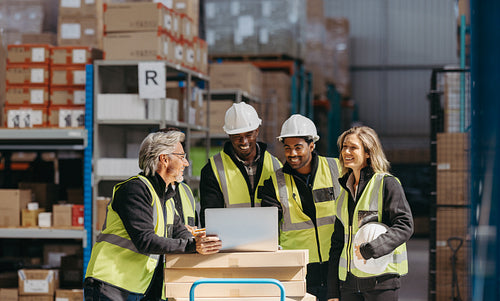 Warehouse staff smiling happily while watching a slideshow presentation on a laptop