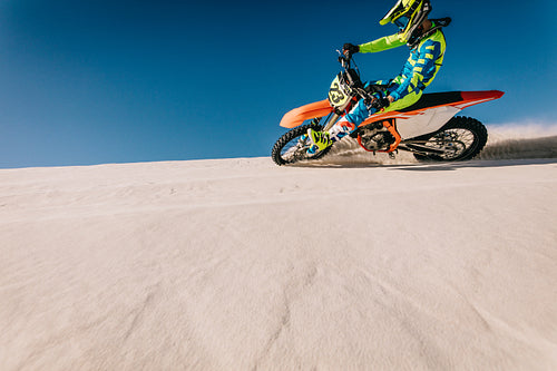 Professional motocross biker riding on sand dunes