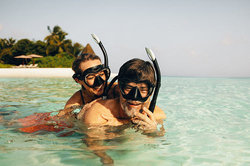 Mature couple snorkeling in clear sea water during vacation at a tropical resort