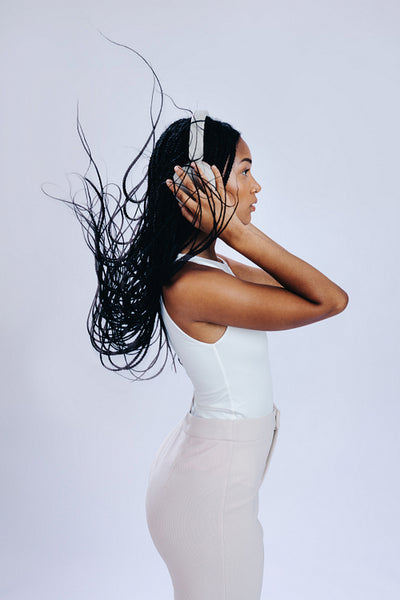 Young woman with black braids listening to music on headphones