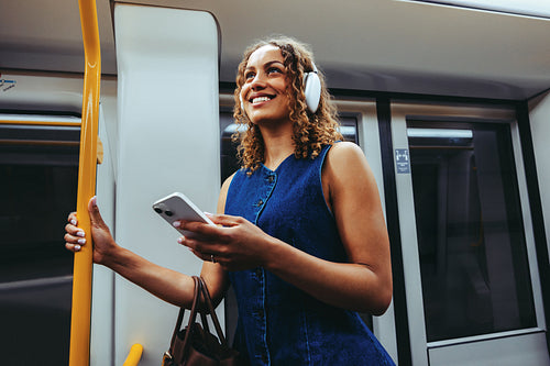 Happy woman checks smartphone while commuting on subway