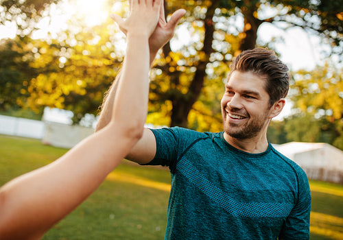 Fitness couple giving high five in park.