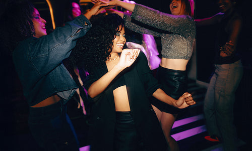 Group of young friends dancing together at a vibrant nightclub