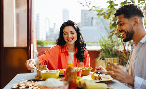 Smiling Latin American friends sharing a meal outdoors on a sunny day