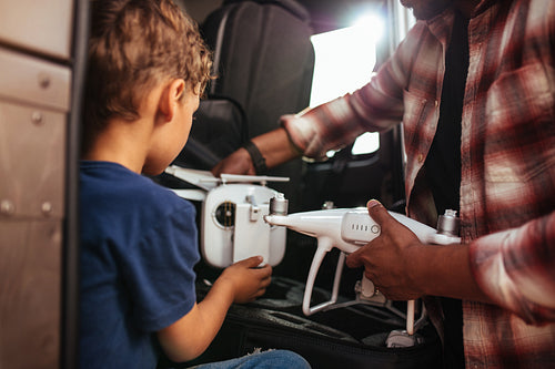 Young boy with father holding small drone on road trip