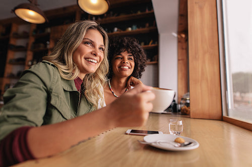 Two young woman sitting at cafe and having coffee