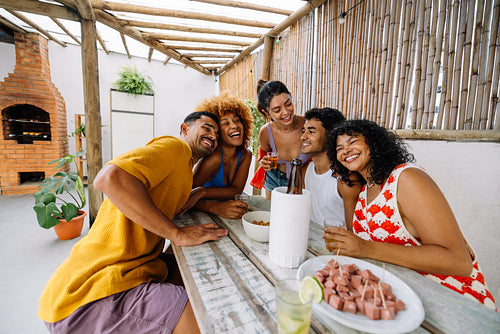 Group of friends enjoying petiscos and drinks in a backyard together