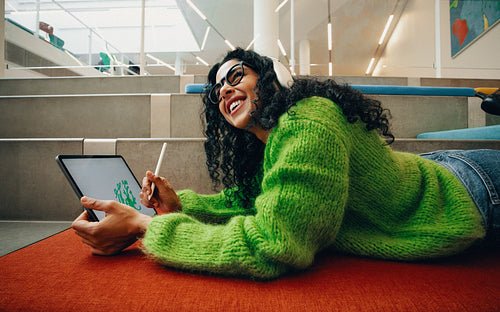 Young woman creating digital art on tablet in library setting