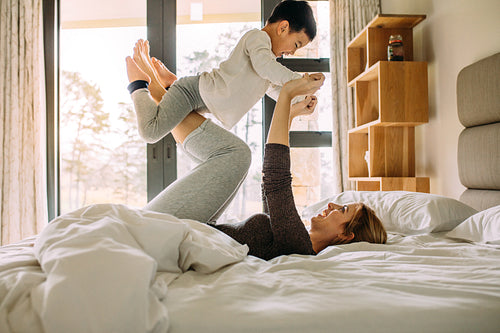 Young family having fun while playing on bed