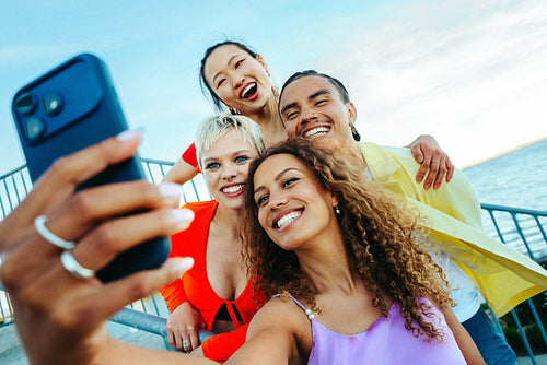 Friends taking a joyful selfie by the waterfront on summer vacation