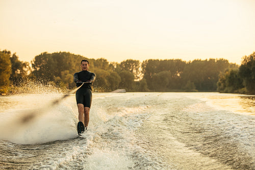 Male water skiing behind a boat on lake