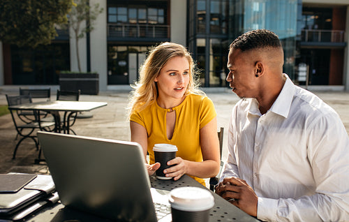 Two business people discussing work at office cafeteria