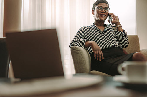 Female CEO relaxing in hotel room and making phone call